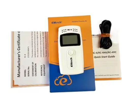 Handheld RC-4 device with display resting on an orange–blue box, with manuals and a black cord beside it.